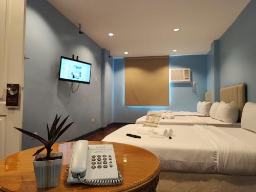 马尼拉Glory Hotel Cubao的酒店客房设有两张床和一张桌子上的电话