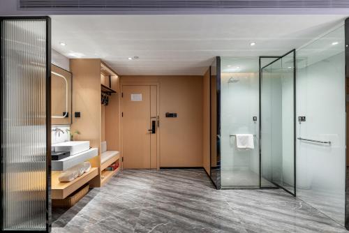 广州金石酒店(广州同和地铁站店)的一间带玻璃淋浴和水槽的浴室