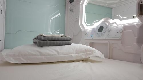 英德Apollo Capsule Hotel的一张带枕头的医院床和一台洗衣机