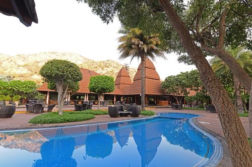 布什格尔Ananta Spa & Resort, Pushkar的棕榈树度假村前的游泳池