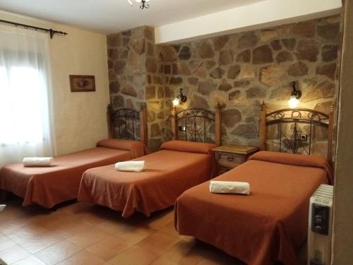 BerzocanaHotel Villa de Berzocana的酒店客房设有两张床和石墙。