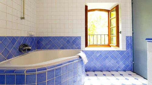 穆斯捷-圣玛丽巴斯蒂德帕拉东酒店的蓝色瓷砖浴室设有浴缸和窗户。