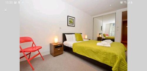 伦敦Luxury Holiday Let @ London City的一间卧室配有一张床和一张红色椅子