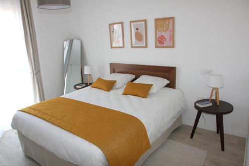 瑟堡DOMITYS LES SALINES的卧室配有一张带白色床单和橙色枕头的大床。