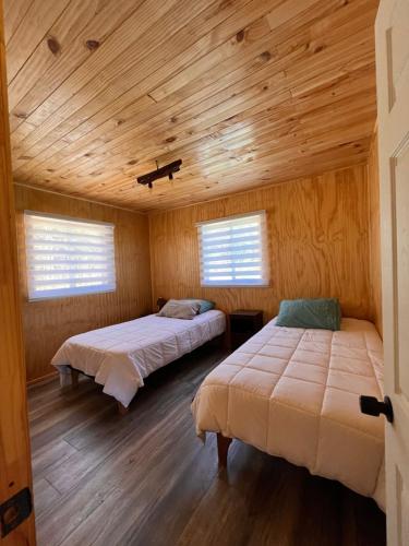 艾森港Cabañas Rio Pangal的配有木天花板的客房设有两张床。