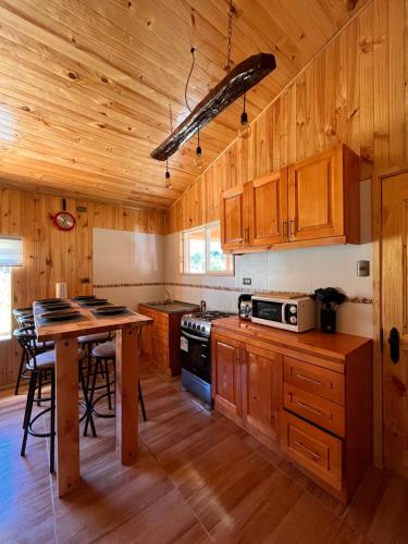 艾森港Cabañas Rio Pangal的厨房配有木制橱柜和带微波炉的桌子。