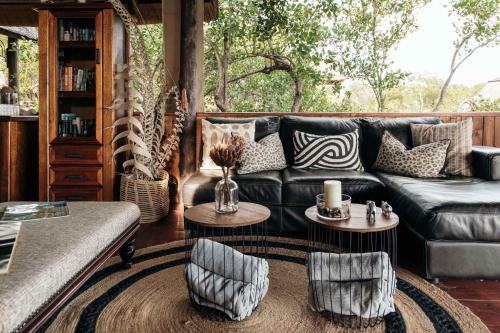 巴卢莱自然保护区Isambane Camp的客厅配有真皮沙发和2张桌子