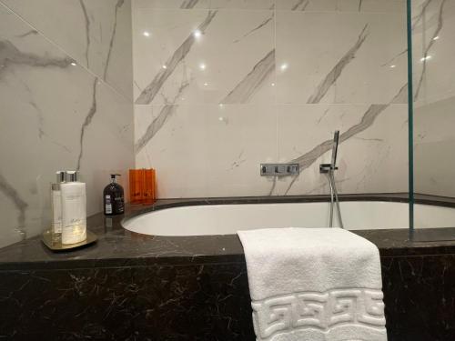 齐格威尔Sophisticated 1BR, 1 BA Chigwell Designer Flat CHCL F2的带浴缸的浴室,在柜台上配有毛巾