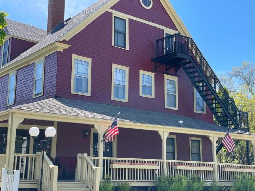巴港Central House Inn的一座紫色的房子,上面有两面美国国旗