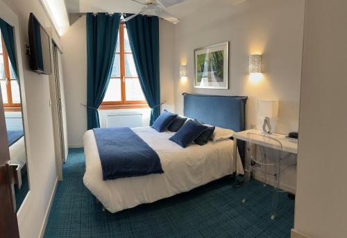 阿尔布瓦Logis Hôtel des Messageries的一间卧室配有一张带蓝色枕头的床和一张书桌