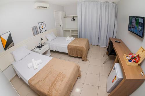 佩内杜Hotel Rochedo AL的小房间设有两张床和一张书桌