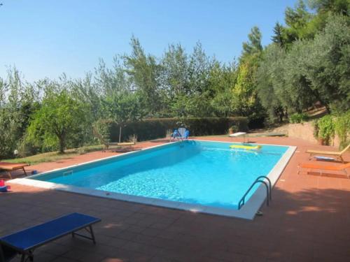 安科纳Casale della Luna的一座大游泳池,位于一个树木繁茂的庭院内