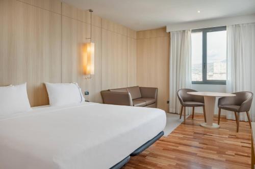 马拉加AC Hotel Málaga Palacio by Marriott的酒店客房带一张床、一张桌子和椅子