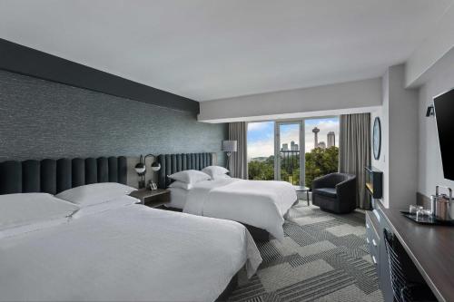 尼亚加拉瀑布Sheraton Fallsview Hotel的酒店客房设有三张床和大窗户