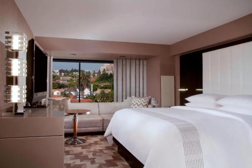 洛杉矶贝弗利山万豪酒店的卧室配有一张白色的大床和一张沙发。