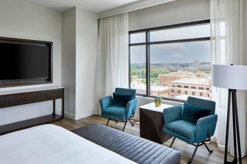 夏洛特UNC Charlotte Marriott Hotel & Conference Center的酒店客房配有一张床、两把椅子和一台电视