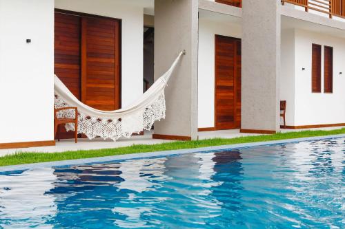 佩德拉斯港Pousada Praia do Patacho的一个带吊床和游泳池的房子