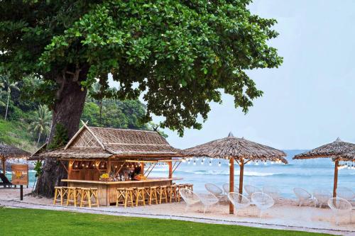 芭东海滩Phuket Marriott Resort & Spa, Merlin Beach的海滩上的酒吧配有椅子和遮阳伞