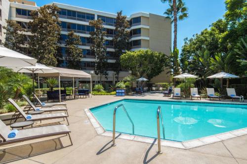 福乐顿市加州州立大学富勒顿万豪酒店的一个带躺椅和遮阳伞的酒店游泳池