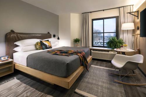 孟菲斯MOXY Memphis Downtown的卧室配有床、椅子和窗户。