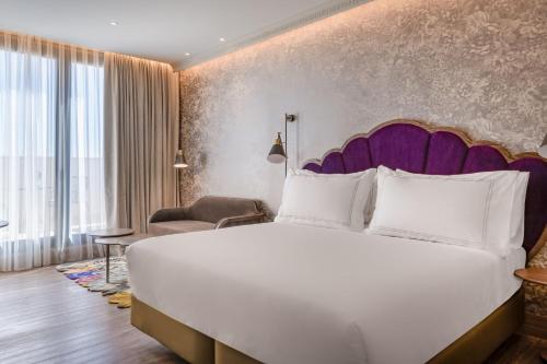 塞维利亚Querencia de Sevilla, Autograph Collection的一间卧室配有一张白色大床和紫色床头板