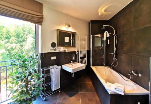 美因河畔奥伯恩堡Hotel Gutsmühle的带浴缸、水槽和镜子的浴室