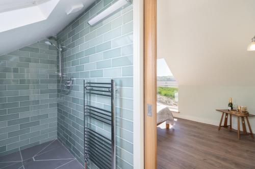 戈斯兰Green End Farm Cottages - The Cow Barn的浴室设有蓝色瓷砖淋浴。