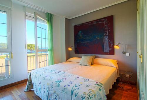 桑坦德El Rincón del Puerto的卧室配有一张床,墙上挂有绘画作品