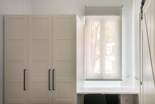 马德里Loft Retiro的白色的厨房配有白色橱柜和窗户