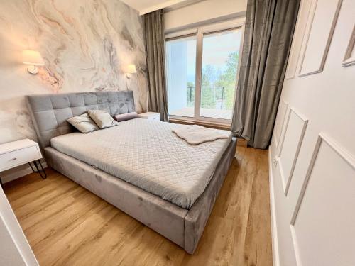 济夫努夫Apartament Superior & SPA Marina Dziwnów的一间卧室设有一张床和一个大窗户