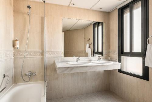 巴达霍斯Hotel Rio Badajoz的一间带两个盥洗盆和淋浴的浴室
