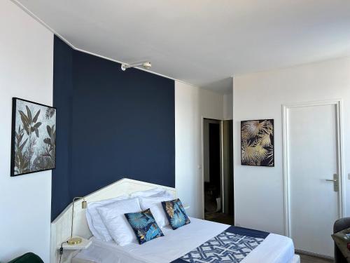 艾吉纳Gabrielle hôtel的一间卧室设有蓝色的墙壁和一张带枕头的床。