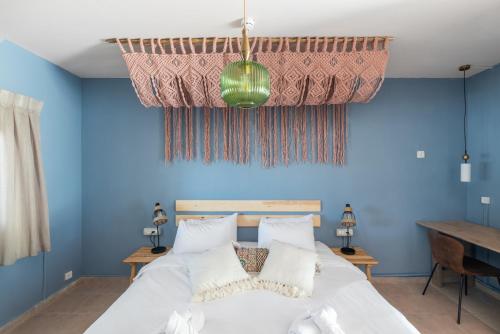 阿尔莫格Selina Mantur Almog Dead Sea的一间卧室拥有蓝色的墙壁,配有一张带白色枕头的床。