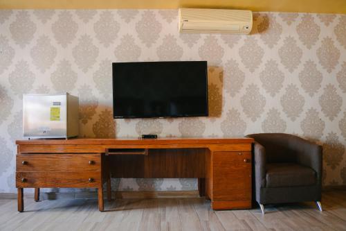 萨卡特卡斯圣卢西亚酒店的一张带椅子的木桌上方的电视机