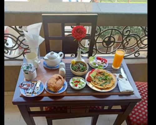 法尤姆Queen Hotel Fayoum的阳台上的早餐桌,包括食物和饮料