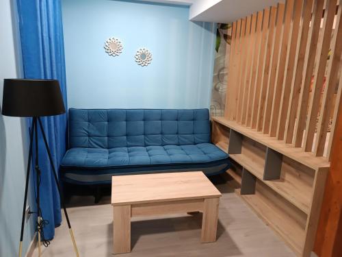 莱昂Hostal Platerías的客厅配有一张蓝色的沙发,配有一张桌子
