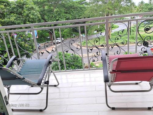 BouéniETOILE DU SUD的两把椅子坐在阳台上,眺望着街道