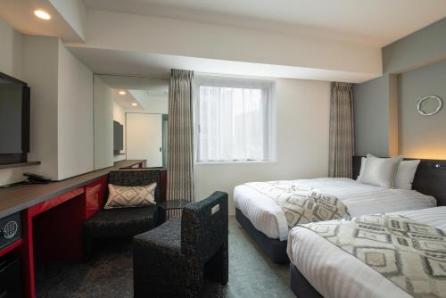 东京Hotel Vista Tokyo Tsukiji的酒店客房设有两张床和电视。