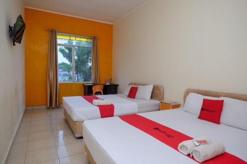 美娜多RedDoorz near Jalan Wolter Monginsidi Manado的橙色墙壁和窗户的客房内的两张床