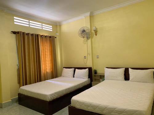 Phumĭ Chŏng KaôhHeangKanha GuestHouse的一间卧室配有两张床和风扇