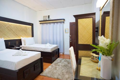 塔比拉兰道戴梦得餐厅及酒店的酒店客房设有两张床和一张桌子,桌子上配有四柱床。