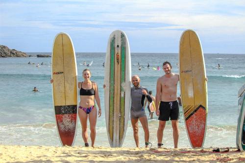 韦利格默Nature Rex Hostel的三人站在海滩上,并有冲浪板