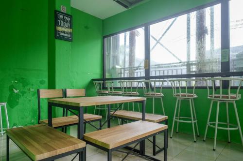 PanikiRedDoorz near Politeknik Manado的绿色的客房配有木桌和椅子