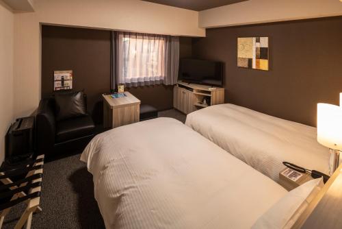 松山Hotel Route Inn Matsuyama -Katsuyama Dori-的酒店客房,配有两张床和椅子