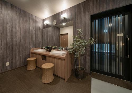 IzumiHotel Route Inn Osaka Izumifuchu的浴室设有水槽、镜子和凳子