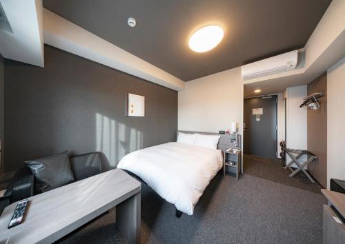 IzumiHotel Route Inn Osaka Izumifuchu的酒店客房,配有床、沙发和床、四柱床和四柱床。