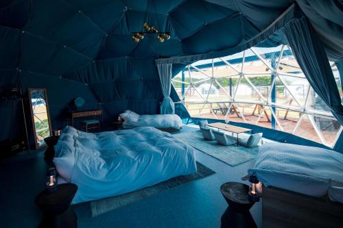 IsumiISUMI Glamping Resort ＆Spa SOLAS的蓝色的客房设有两张床和大窗户
