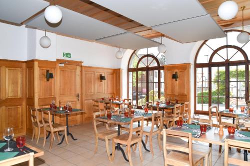 OllonHôtel de Ville d'Ollon的餐厅设有木桌、椅子和窗户。
