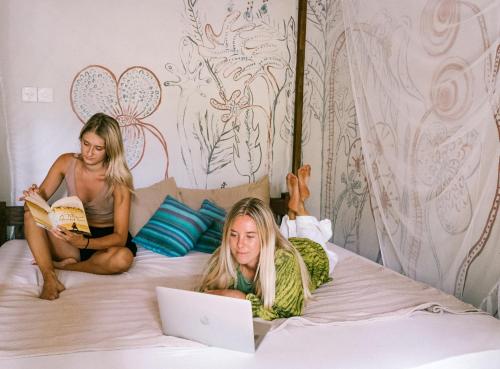 阿杭格默Mellow Hostel Sri Lanka的两名女孩躺在床上,手提电脑