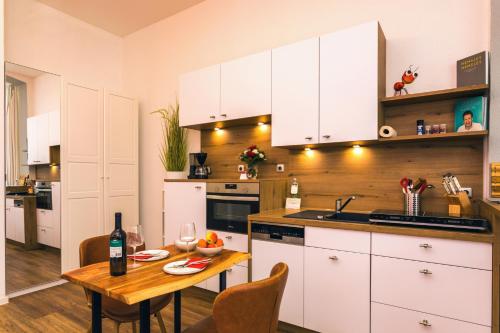 赛巴特班森Villa Anna - Rubin的厨房配有白色橱柜和1张带1瓶葡萄酒的桌子
